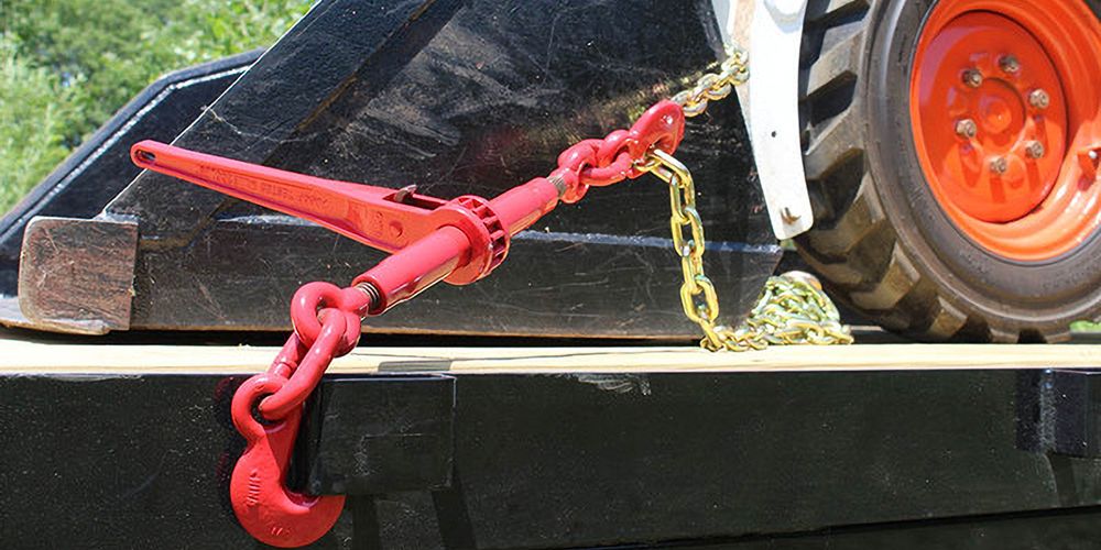 chain and ratchet binder securing a skid steer to a flatbed trailer